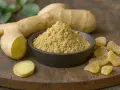 Gingembre cru, poudre et confit sur une planche en bois. Une racine de gingembre coupée révèle sa chair jaune vif.
