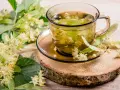 Une tasse de thé de tilleul, aux fleurs et feuilles fraîches, évoquant ses bienfaits apaisants.