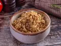 Un bol de quinoa, riche en fibres, prêt à être dégusté. Des tomates rouges et une branche de romarin complètent la scène.