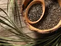 Graines de chia dans une écorce de noix de coco, une cuillère en bois remplie de ces petites graines. Un aliment idéal pour une femme enceinte.