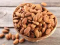 Un panier rempli d'amandes sur fond de bois. Savoir pourquoi faire tremper les amandes améliore leur digestibilité et leur saveur.
