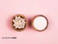 Deux bols en bois sur fond rose : l'un rempli de gélules nacrées, l'autre de poudre blanche. Le collagène hydrolysé danger potentiel est-il présent ?