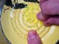 Main d'une personne râpe du gingembre sur une râpe jaune décorée.