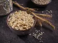 Un bol de perles d'orge cuites, avec des épis et des grains d'orge, évoquant les nombreux bienfaits de ce grain.