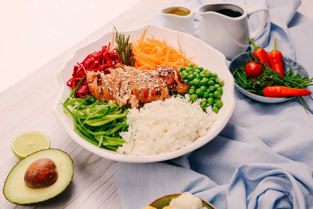 Un bol coloré avec du poulet grillé, du riz, des légumes frais et des épices. Une recette healthy parfaite pour un repas équilibré.
