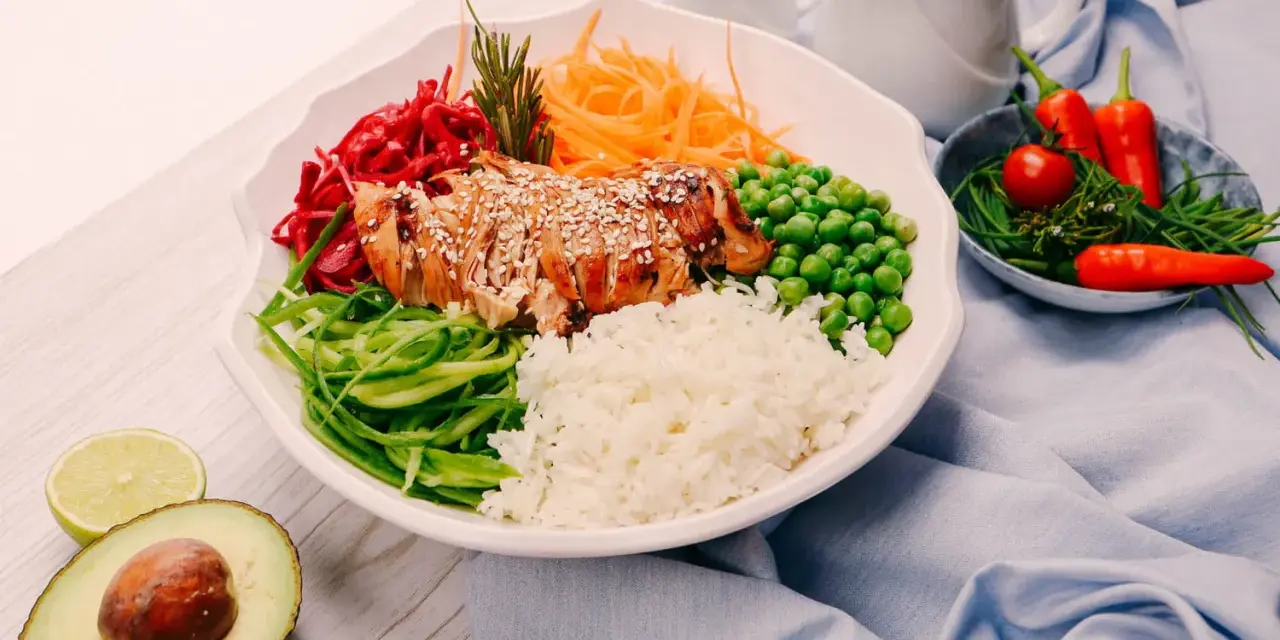 Un bol coloré avec du poulet grillé, du riz, des légumes frais et des épices. Une recette healthy parfaite pour un repas équilibré.