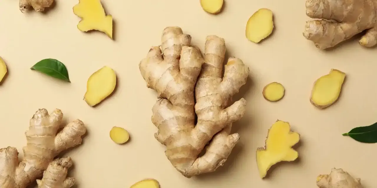 Gingembre frais, en morceaux et en tranches, disposés sur fond beige. Un aperçu de son gingembre effet immédiat.