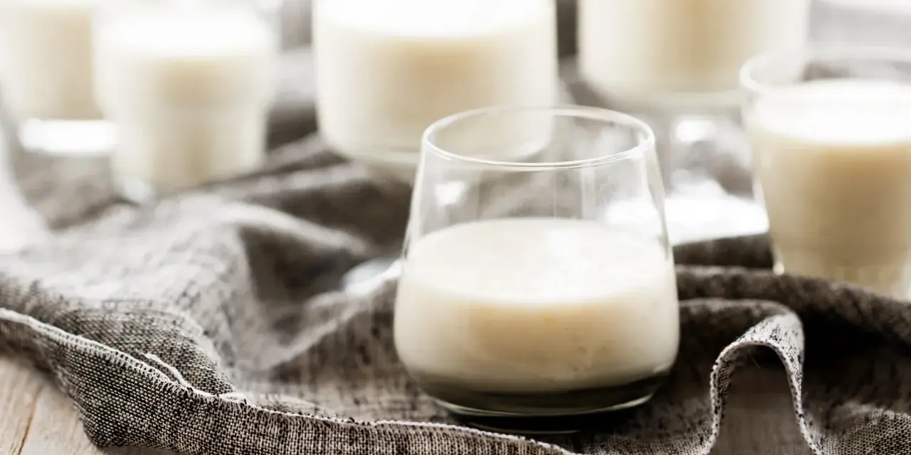 Plusieurs verres remplis de kéfir crémeux, posés sur une serviette grise.