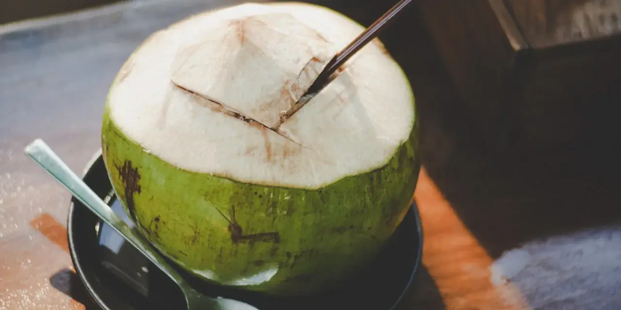 Une noix de coco fraîchement ouverte, prête à être dégustée. L'eau de coco, promesse d'une hydratation pure, est un délice qui ne trompe jamais.