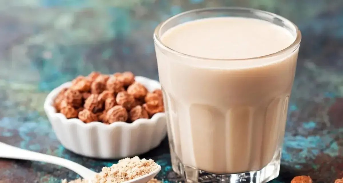 Un verre de lait de souchet crémeux, à côté d'une coupelle de tubercules et d'une cuillère de poudre.