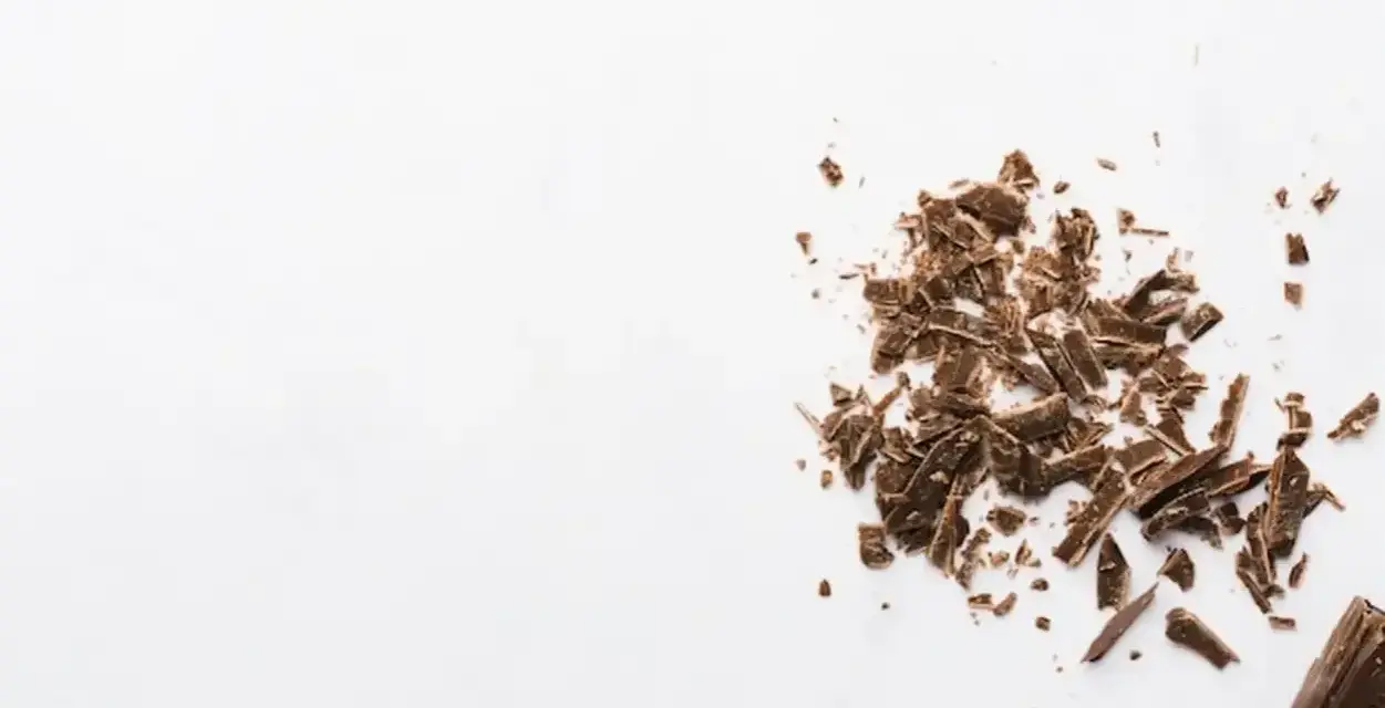 Éclats de grué de cacao sur fond blanc, rappelant les nombreux bienfaits de cet ingrédient naturel.