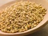 Graines de fenugrec sur une cuillère en bois, une aide naturelle pour gérer l'hypertension.