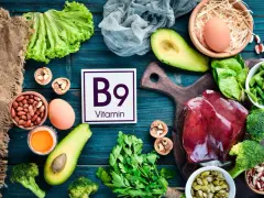 Assiette colorée avec foie, légumes verts, avocats, œufs, noix et haricots, mettant en avant la vitamine B9 essentielle.