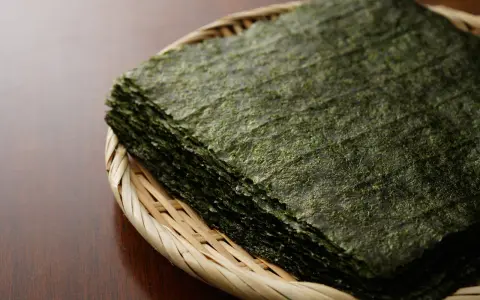Feuilles d'algue nori empilées dans un panier en osier. Attention, certaines algues peuvent contenir des traces de métaux lourds, un danger potentiel.