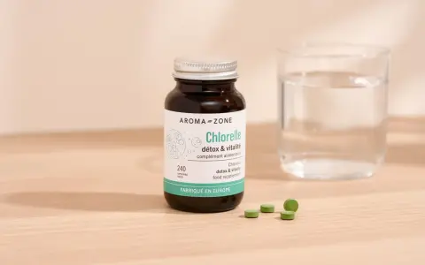 Bouteille de chlorelle Aroma-Zone, 240 comprimés. Pour une cure détox et vitalité, combien de temps faut-il ? Verre d'eau à côté.
