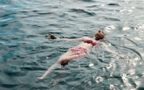 Une femme flotte paisiblement sur l'eau, profitant des ampoules eau de mer bienfaits pour la relaxation et le bien-être.