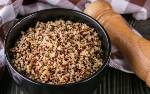 Un bol de quinoa, un aliment polyvalent, est-il un féculent ou une légumineuse ? Servi avec une serviette à carreaux et un moulin à poivre en bois.