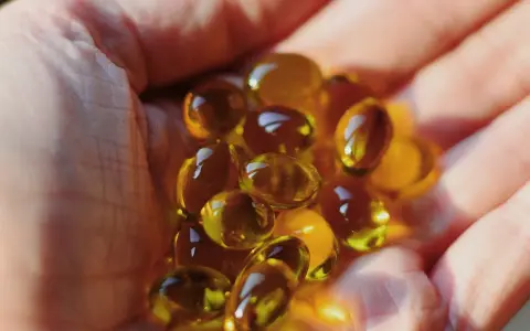Une main tient des capsules d'huile de bourrache et onagre, un soutien naturel pour la ménopause.
