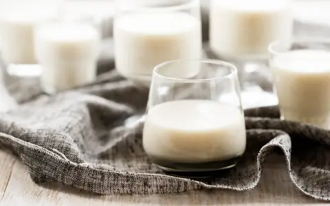 Plusieurs verres remplis de kéfir crémeux, posés sur une serviette grise.
