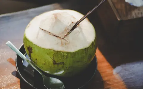 Une noix de coco fraîchement ouverte, prête à être dégustée. L'eau de coco, promesse d'une hydratation pure, est un délice qui ne trompe jamais.