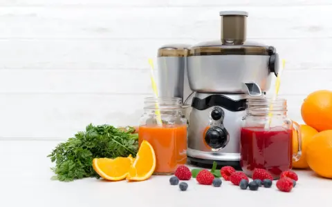 Une centrifugeuse ou extracteur prépare des jus frais avec des fruits et légumes. Ici, des jus d'orange, de carotte et de baies, avec des oranges, des carottes et des baies.