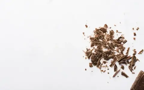 Éclats de grué de cacao sur fond blanc, rappelant les nombreux bienfaits de cet ingrédient naturel.
