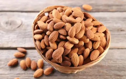 Un panier rempli d'amandes sur fond de bois. Savoir pourquoi faire tremper les amandes améliore leur digestibilité et leur saveur.