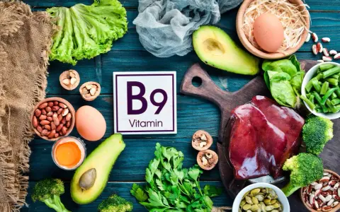 Assiette colorée avec foie, légumes verts, avocats, œufs, noix et haricots, mettant en avant la vitamine B9 essentielle.