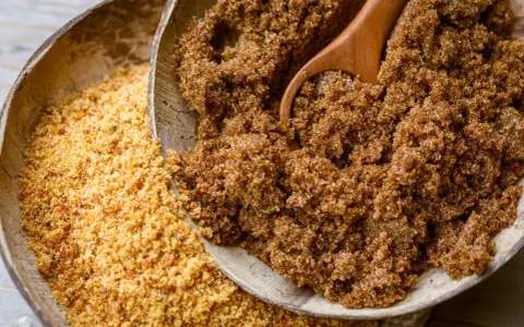 Deux bols en bois remplis de sucre : l'un de rapadura, l'autre de sucre de coco.