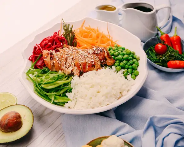 Un bol coloré avec du poulet grillé, du riz, des légumes frais et des épices. Une recette healthy parfaite pour un repas équilibré.