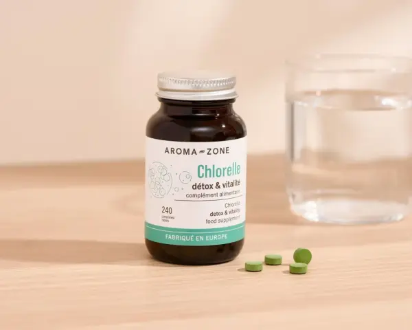 Bouteille de chlorelle Aroma-Zone, 240 comprimés. Pour une cure détox et vitalité, combien de temps faut-il ? Verre d'eau à côté.