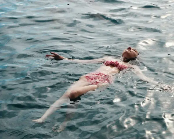 Une femme flotte paisiblement sur l'eau, profitant des ampoules eau de mer bienfaits pour la relaxation et le bien-être.