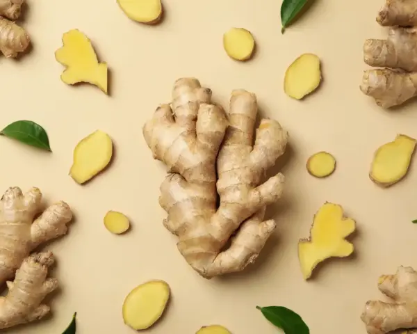 Gingembre frais, en morceaux et en tranches, disposés sur fond beige. Un aperçu de son gingembre effet immédiat.