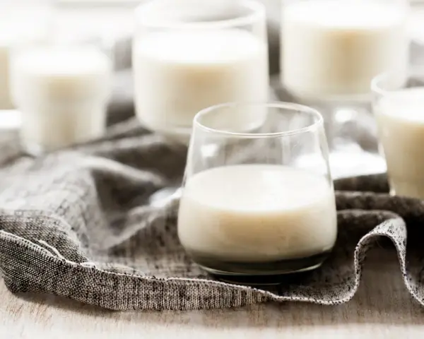 Plusieurs verres remplis de kéfir crémeux, posés sur une serviette grise.