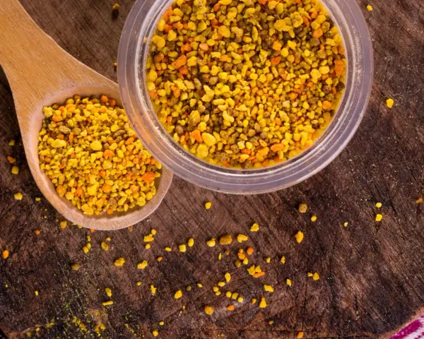 Une cuillère en bois et un pot remplis de pollen d'abeille, un concentré de bienfaits naturels.