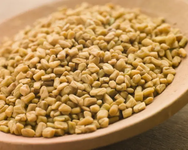 Graines de fenugrec sur une cuillère en bois, une aide naturelle pour gérer l'hypertension.