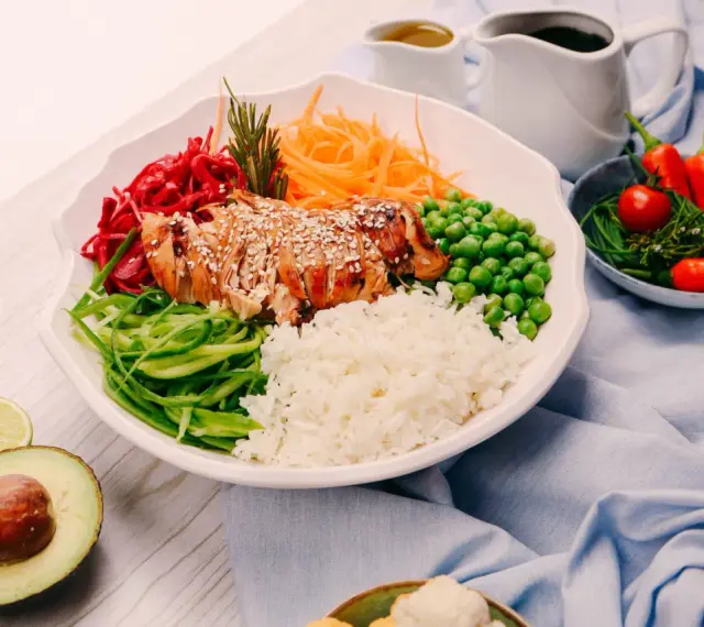 Un bol coloré avec du poulet grillé, du riz, des légumes frais et des épices. Une recette healthy parfaite pour un repas équilibré.