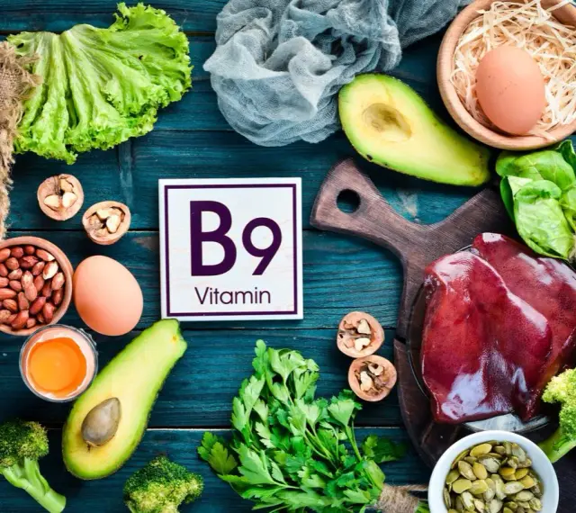Assiette colorée avec foie, légumes verts, avocats, œufs, noix et haricots, mettant en avant la vitamine B9 essentielle.