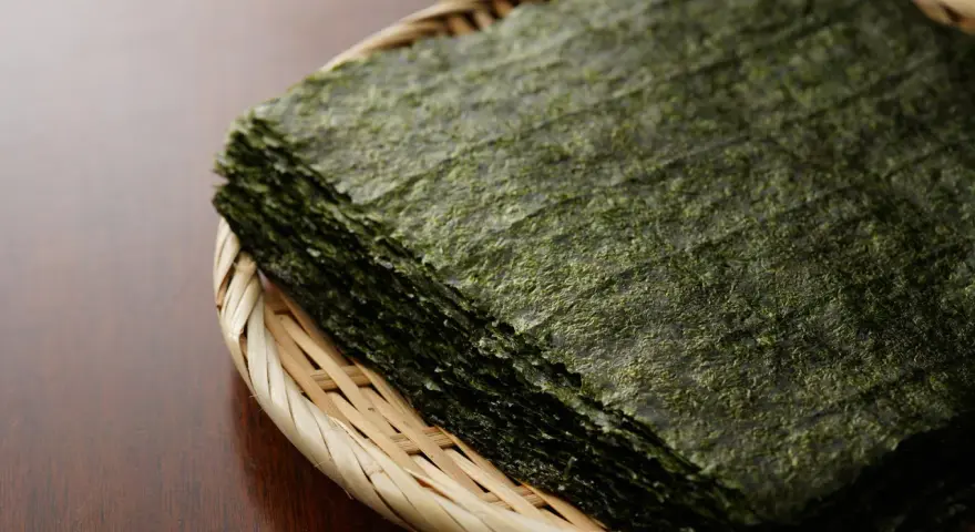 Feuilles d'algue nori empilées dans un panier en osier. Attention, certaines algues peuvent contenir des traces de métaux lourds, un danger potentiel.