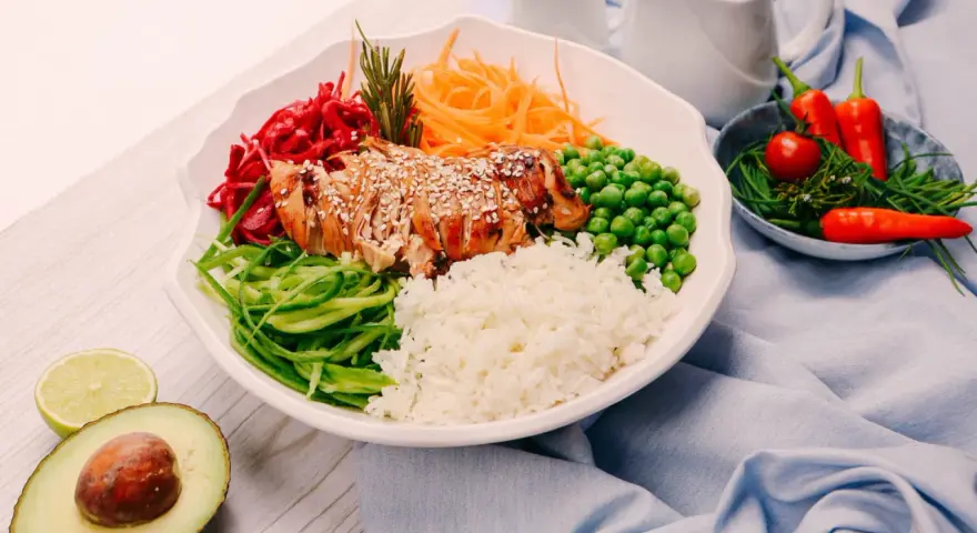 Un bol coloré avec du poulet grillé, du riz, des légumes frais et des épices. Une recette healthy parfaite pour un repas équilibré.