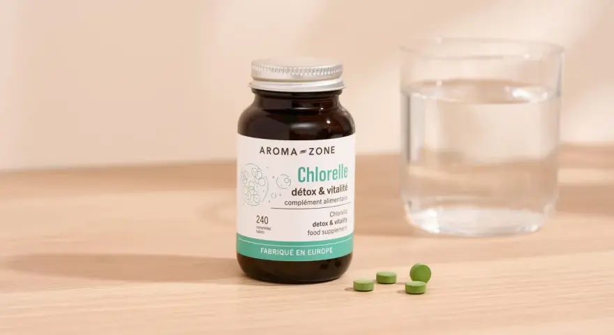Bouteille de chlorelle Aroma-Zone, 240 comprimés. Pour une cure détox et vitalité, combien de temps faut-il ? Verre d'eau à côté.