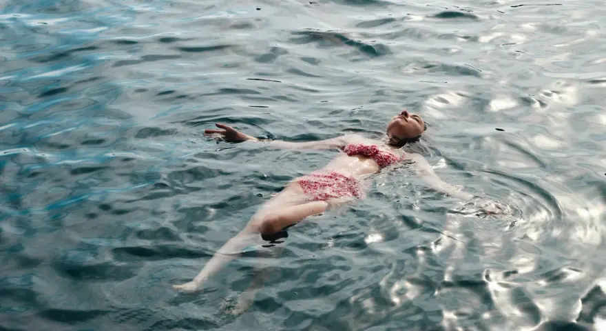 Une femme flotte paisiblement sur l'eau, profitant des ampoules eau de mer bienfaits pour la relaxation et le bien-être.