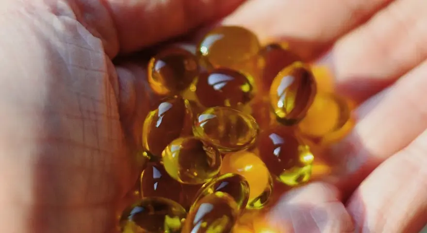 Une main tient des capsules d'huile de bourrache et onagre, un soutien naturel pour la ménopause.