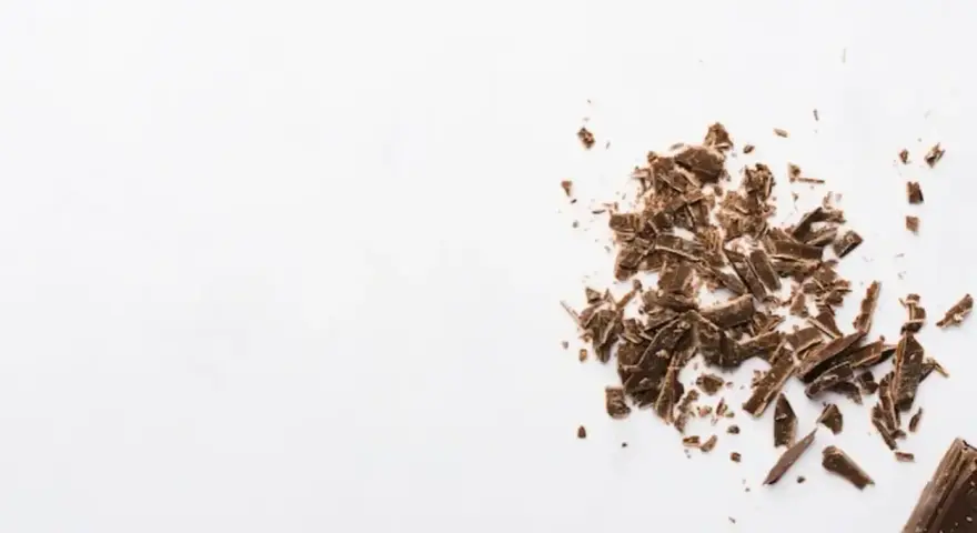Éclats de grué de cacao sur fond blanc, rappelant les nombreux bienfaits de cet ingrédient naturel.