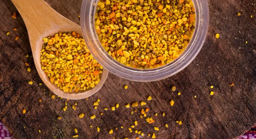 Une cuillère en bois et un pot remplis de pollen d'abeille, un concentré de bienfaits naturels.