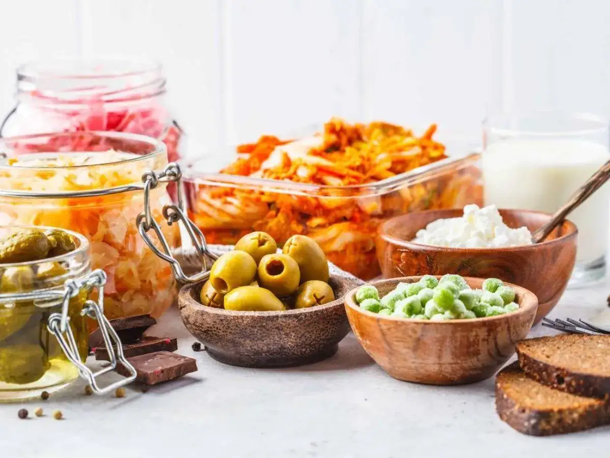 Une s&eacute;lection d'aliments ferment&eacute;s : choucroute, kimchi, cornichons, olives, yaourt, lait, pois et pain de seigle.