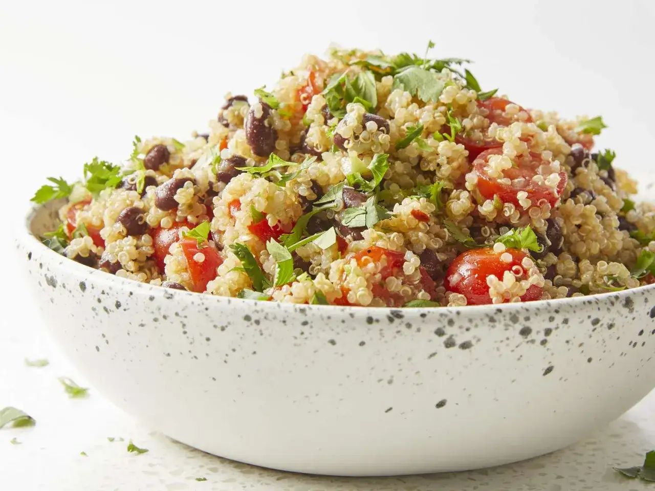 Salade de quinoa colorée avec tomates cerises, haricots noirs et coriandre fraîche. Un plat savoureux qui met en avant la nutrition du quinoa.