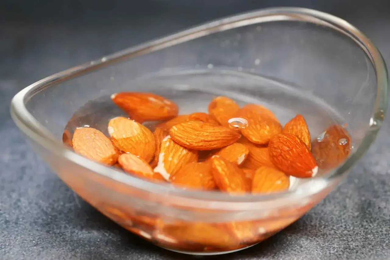 Amandes dans un bol d'eau, prêtes à être trempées. Savoir pourquoi faire tremper les amandes améliore leur digestibilité et leur saveur.