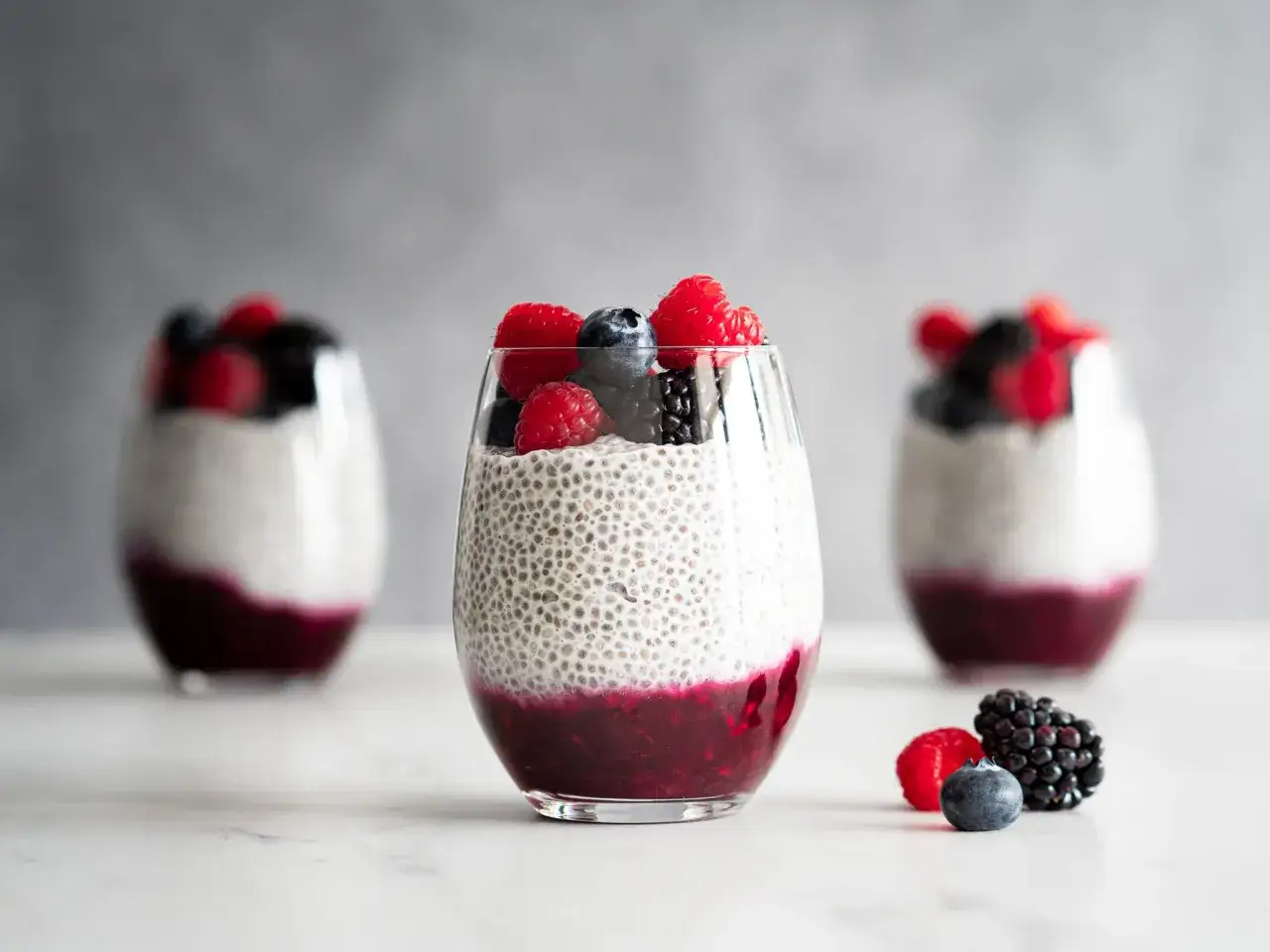 Trois verres de pudding de chia aux fruits rouges et baies. Un délice sain et coloré.