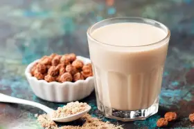 Un verre de lait de souchet crémeux, à côté d'une coupelle de tubercules et d'une cuillère de poudre.